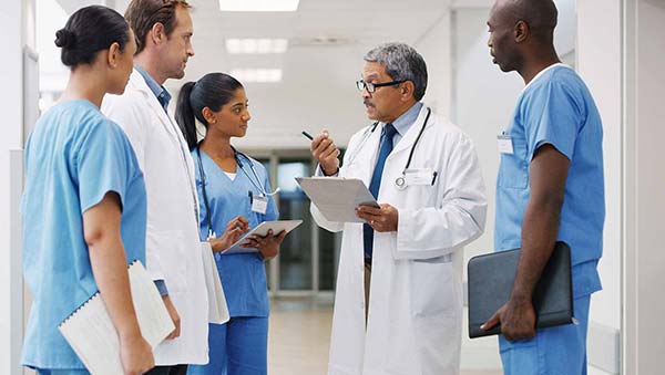 Nurses standing around head doctor.